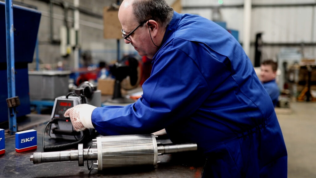 Engineer inspecting a stripped drive shaft and bearings during a repair